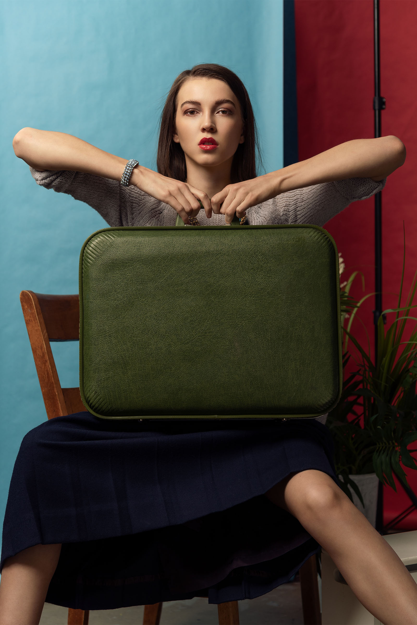 High fashion studio portrait of a female model holding up a vintage suitcase by Christopher Loke.